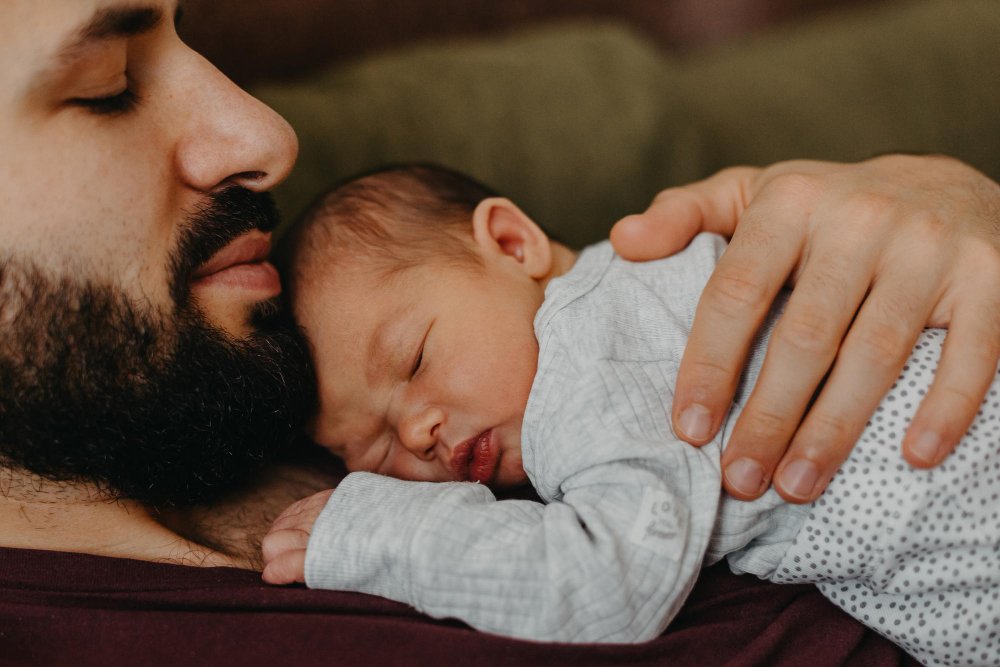 Padre abrazando a su bebé dormido, mejorando el sueño de tu bebé.