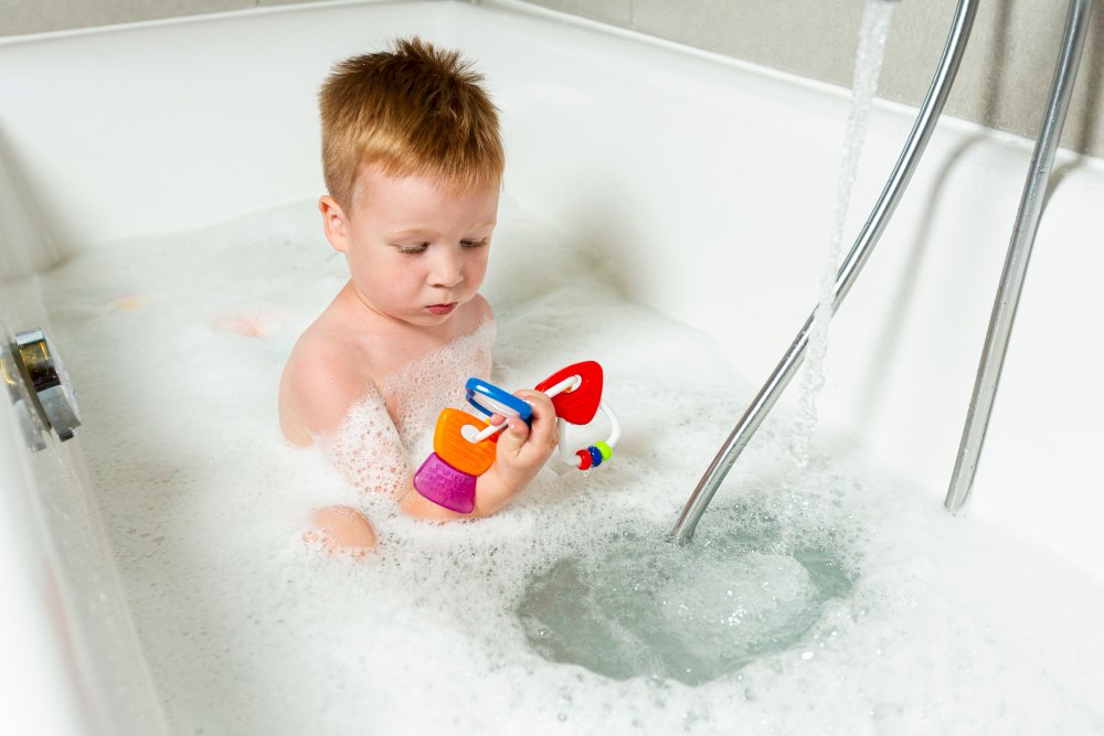 Niño jugando en la bañera, un recordatorio de los riesgos de ahogamiento y resbalones en el baño.